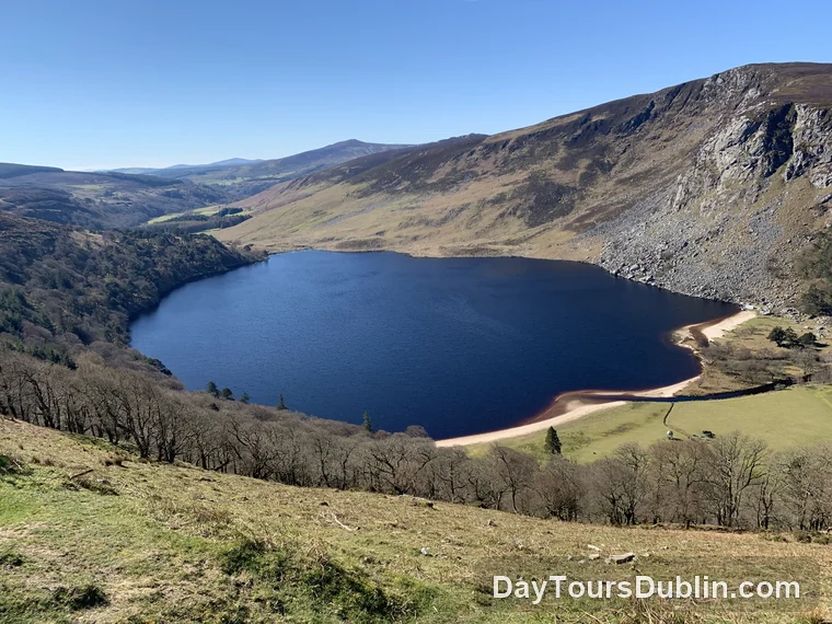 Lough Tay in County Wicklow, a dark lake with a pale sandy shore below steep mountain slopes